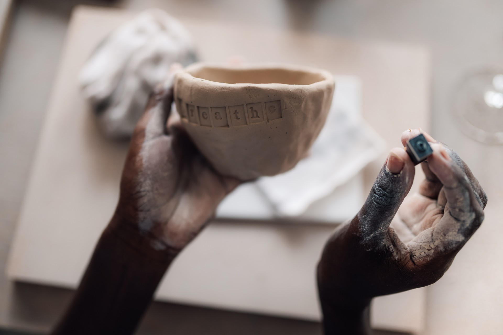 Close up of diverse artisan decorating clay work at pottery workshop.