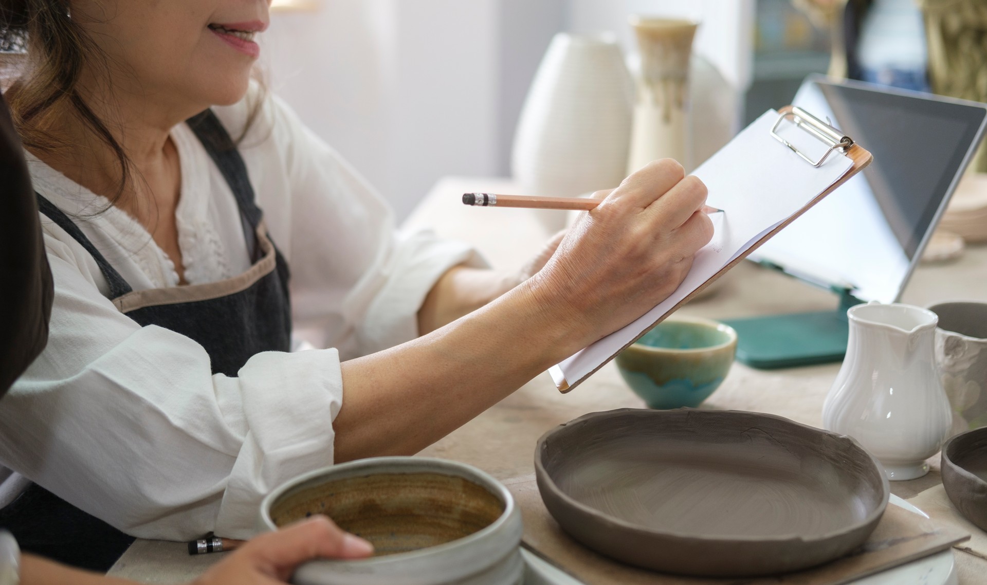 Middle aged woman preparing handmade ceramic products order, working in her craft pottery shop handmade ceramic products. Young female entrepreneurs running a creative small business.